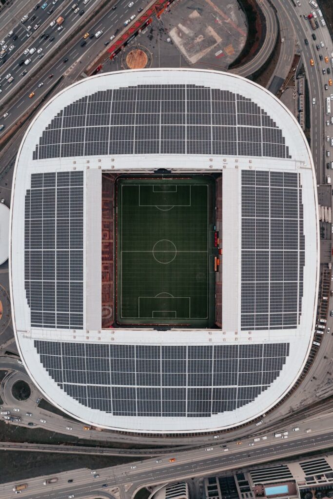 Top view of a solar-panel-covered soccer stadium, capturing surrounding roads.